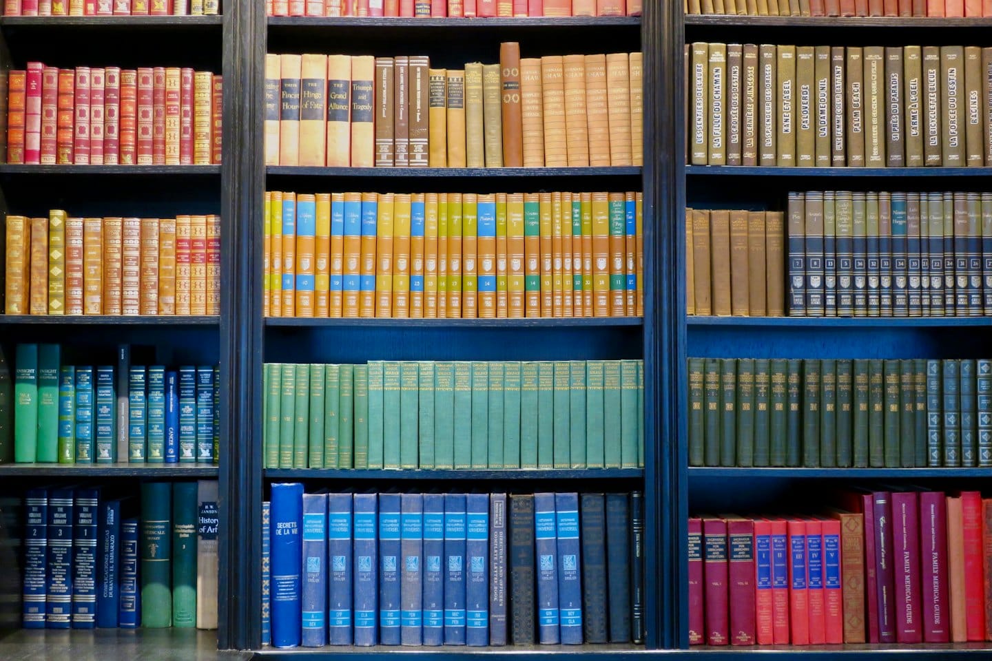 Vägg av gamla böcker som fyller många hyllor i ett bibliotek.